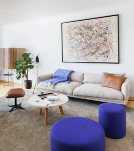 Wohnzimmer mit großem Gemälde und blauen Puffs